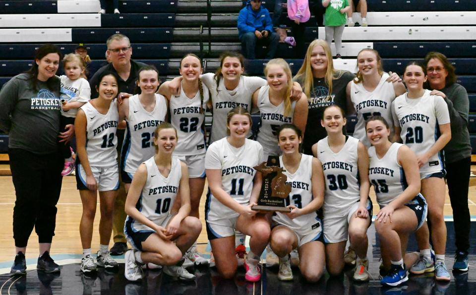 The Petoskey girls' basketball team gathers at center court with a Division 2 district championship trophy after topping Kingsley Friday night in their home gym. It's the first title since 2020-21 for PHS.