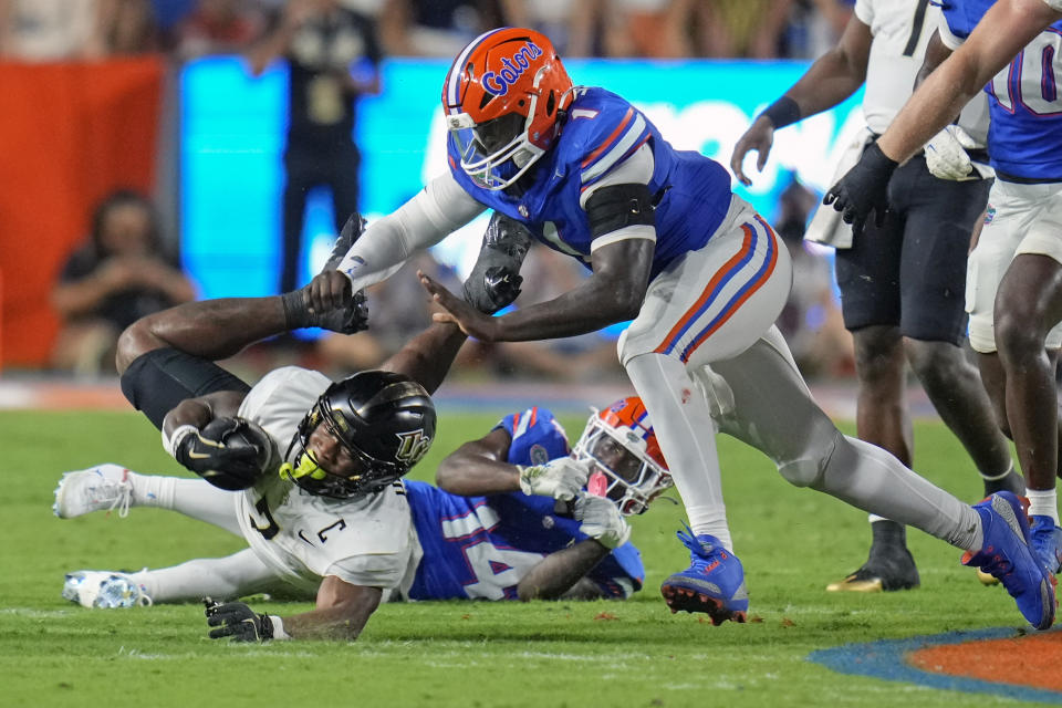 Central Florida running back RJ Harvey, left, dives for extra yardage as he is stopped by Florida defensive back Jordan Castell, center, and edge Justus Boone during the first half of an NCAA college football game, Saturday, Oct. 5, 2024, in Gainesville, Fla. (AP Photo/John Raoux)