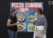 People, social distancing and wearing masks to prevent the spread of the new coronavirus, wait in line at a mask distribution event, Friday, June 26, 2020, in a COVID-19 hotspot of the Little Havana neighborhood of Miami. Florida banned alcohol consumption at its bars Friday as its daily confirmed coronavirus cases neared 9,000, a new record that is almost double the previous mark set just two days ago. (AP Photo/Wilfredo Lee)