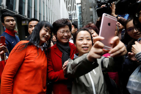 People take selfies with Carrie Lam, chief executive-elect, a day after she was elected in Hong Kong. REUTERS/Tyrone Siu