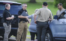 A Morgan County, Ala. investigators gather information from a woman at the scene, Friday, June 5, 2020, in Valhermoso Springs, Ala., where numerous people were found fatally shot. Deputies responding to a call about a shooting in Alabama found seven people dead inside a home that had been set afire early Friday, authorities said. (Jeronimo Nisa/The Decatur Daily via AP)