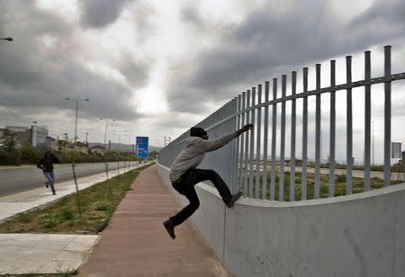 An African immigrant tries to jump a fence into a ferry terminal in the western Greek town of Patras April 28, 2015. REUTERS/Yannis Behrakis