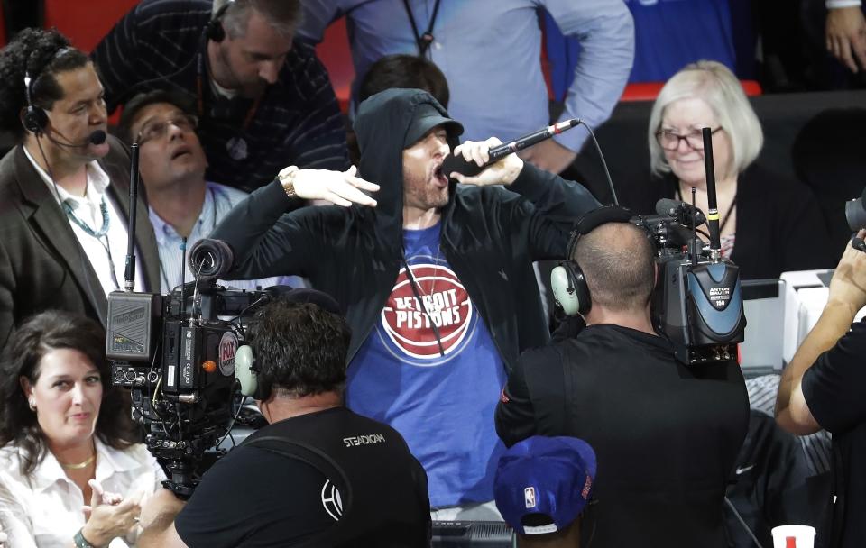 FILE - Eminem yells to the crowd before the start of an NBA basketball game between the Detroit Pistons and the Charlotte Hornets, Oct. 18, 2017, in Detroit. Just as a movie soundtrack helps viewers follow the action of the narrative through each plot twist, hip-hop has done the same for basketball via the NBA. (AP Photo/Carlos Osorio, file)