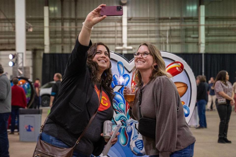 JoAnna Rogers, left, and Jamie Young take a selfie in front of the heart display titled “City Fountains of Sports Color” by artist Julie Flanagan Friday during the Parade of Hearts reveal kickoff event. Emily Curiel/ecuriel@kcstar.com