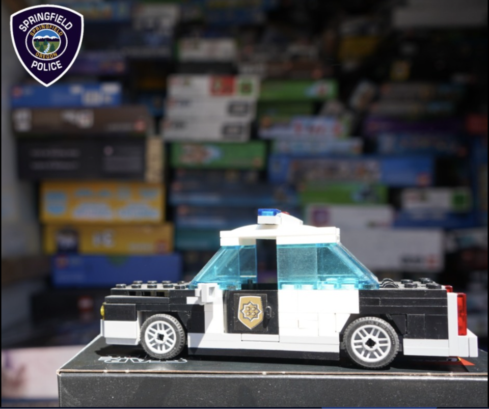 A Lego police car sits in front of a stack of stolen Lego sets recovered in an image shared by the Springfield Police in Oregon. / Credit: Springfield Police Department