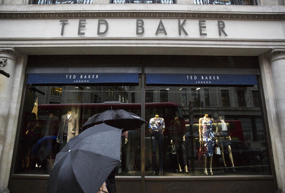 People shelter under umbrellas as they pass a Ted Baker a store in London, Britain October 06, 2015. British designer clothing brand Ted Baker on Tuesday said retail sales were up by just over 20 percent in its first half year, boosted by solid demand at home and a strong performance in North America.   REUTERS/Neil Hall