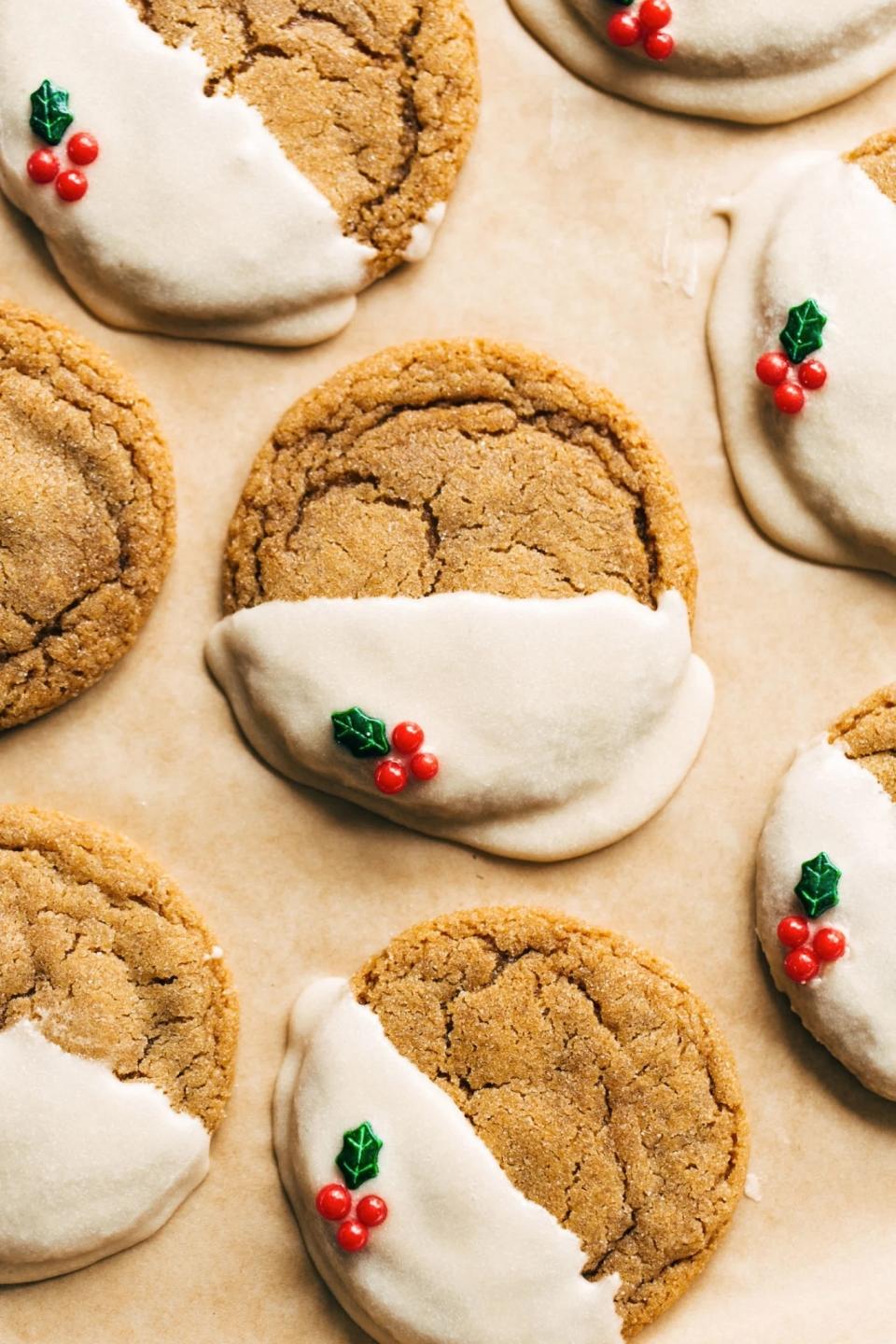 round gingerbread cookies on a sheet tray with glaze and sprinkle decorations covering one half of each cookie