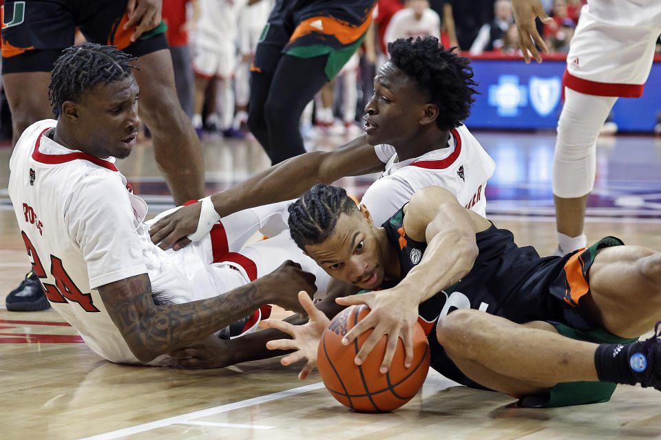 Miami's Isaiah Wong (2) tries to gather in a loose ball with North Carolina State's Ernest Ross (24) and Jarkel Joiner, back, nearby during the second half of an NCAA college basketball game in Raleigh, N.C., Saturday, Jan. 14, 2023. (AP Photo/Karl B DeBlaker)