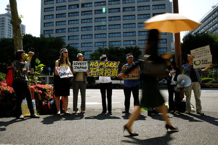 Demonstrators hold anti-fossil fuel placards during a protest in front of the finance minstry in Tokyo ahead of the upcoming Ise-Shima G7 summit, calling on Japan to stop investing in fossil fuels, Japan, May 19, 2016. The placard reads "(No more) fossil fuel investment." REUTERS/Thomas Peter