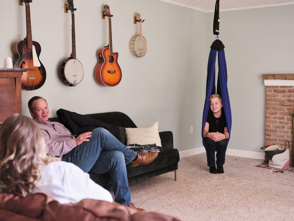 Ayden chats with his parents while sitting in a therapy swing in their home in Ohio. The swing helps Ayden manage some of his pain, allowing him to rest and recharge when he is tired or in pain.<span class="copyright">Julie Renée Jones for TIME</span>