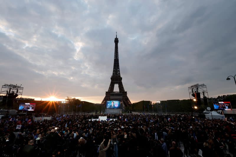 FILE PHOTO: Supporters of French President Emmanuel Macron, candidate for his re-election, react after the results in the second round vote of the 2022 French presidential election, near Eiffel Tower, at the Champs de Mars in Paris