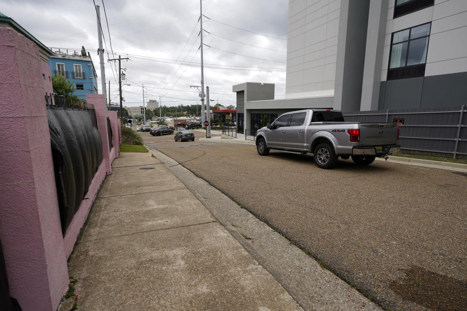 Traffic moves past the Jackson Women's Health Organization clinic, also known as "The Pink House," on the left and a upscale motel on the right, Wednesday, May 19, 2021, in Jackson, Miss. The clinic's fencing is shrouded with a black tarp so that its clients may enter in privacy, while the motel has put up privacy fencing. The Supreme Court agreed to take up a dispute over a Mississippi ban on abortions after 15 weeks of pregnancy, with their decision affecting whether the state's only medical facility will continue to be able to provide abortions on demand. (AP Photo/Rogelio V. Solis)