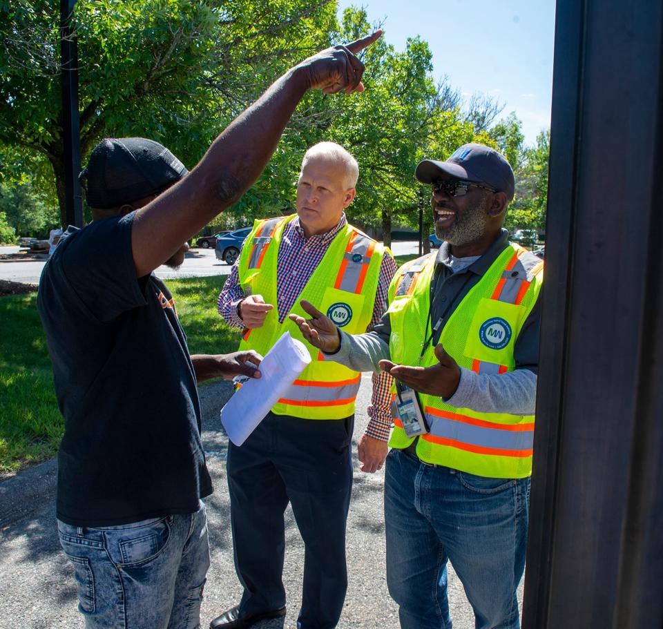 Jon Fetherston, center, then director of community outreach at the MetroWest Regional Transit Authority, and Giovanni Fleurancois, right, general manager for National Express, the MWRTA's transportation provider, instruct Haitian asylum seekers living in Framingham how to use the regional bus service, Aug. 31, 2023.