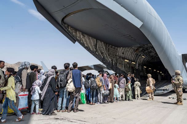 PHOTO: U.S. Airmen and U.S. Marines guide evacuees aboard a U.S. Air Force C-17 Globemaster III in support of the Afghanistan evacuation at Hamid Karzai International Airport in Kabul, Afghanistan, Aug. 21, 2021. (Senior Airman Brennen Lege/USAF)