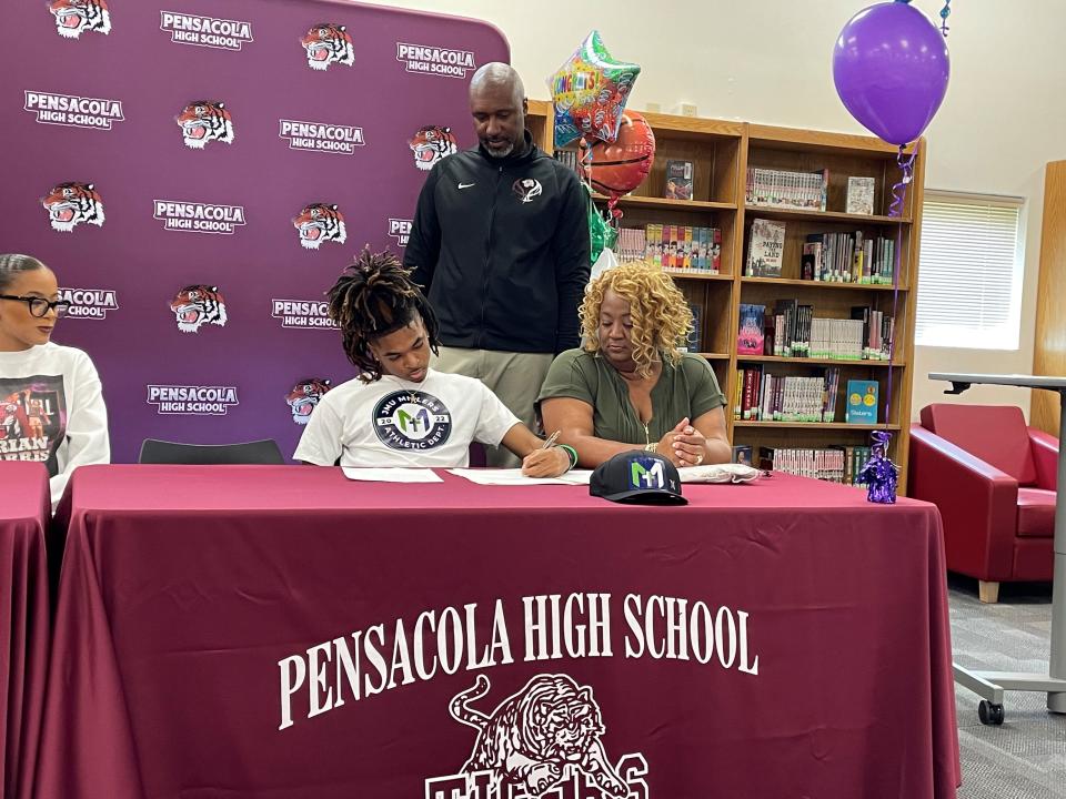 Pensacola High senior Jonah Carter (center seated) signs his letter of intent to play basketball at John Melvin University during a ceremony on Thursday, April 13, 2023 at Pensacola High School.