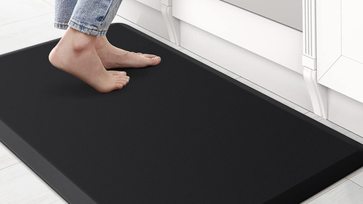 Feet standing on a black kitchen mat