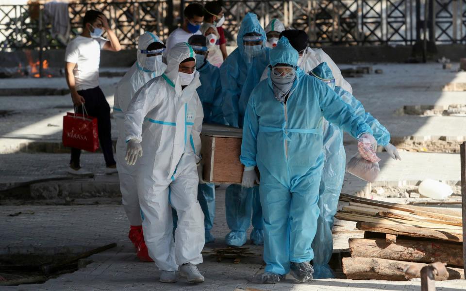 Health workers and relatives carry the body of a COVID-19 victim for cremation in Jammu - AP