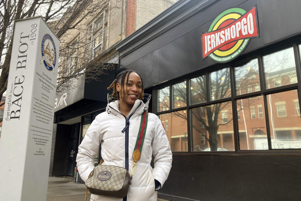 Kadejia Berkley poses outside Jerk Shop Go, the restaurant she owns in downtown Springfield, Ill., Wednesday, March 22, 2023. Berkley, 26, opened the eatery last fall at the site which more than a century ago was home to Loper's Restaurant, which a white mob burned at the start of the 1908 Race Riot when it learned that the wealthy white owner, Harry T. Loper, used his car to squire away to safety two jailed Black men accused of crimes that the mob wanted to lynch. (AP Photo/John O'Connor)