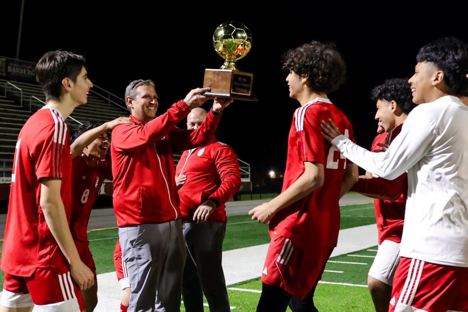 Haughton head coach Michael Marston handing the district championship trophy to his players after the game against Caddo Magnet on Monday, January 29, 2024, at Preston Crownover Stadium.