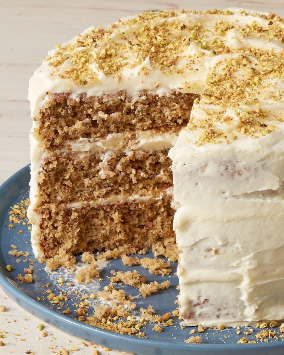 closeup of pistachio cake with a slice missing on a blue plate