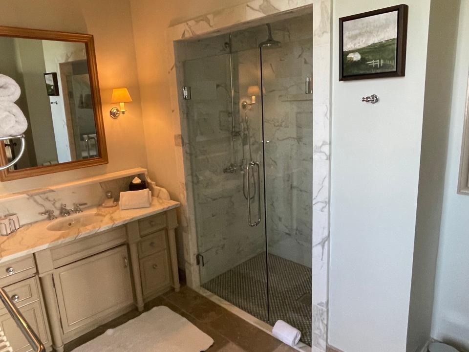 Washroom with a beige cabinets, a marble countertop, and a walk-in glass shower