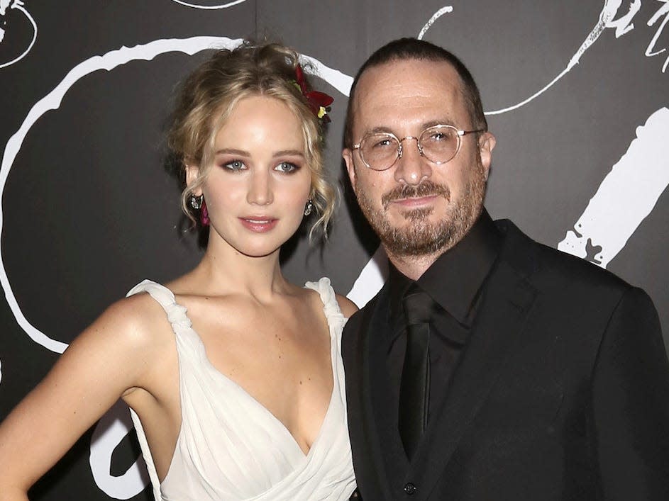 Jennifer Lawrence posing next to Darren Aronofsky while wearing a shite sleeveless dress.