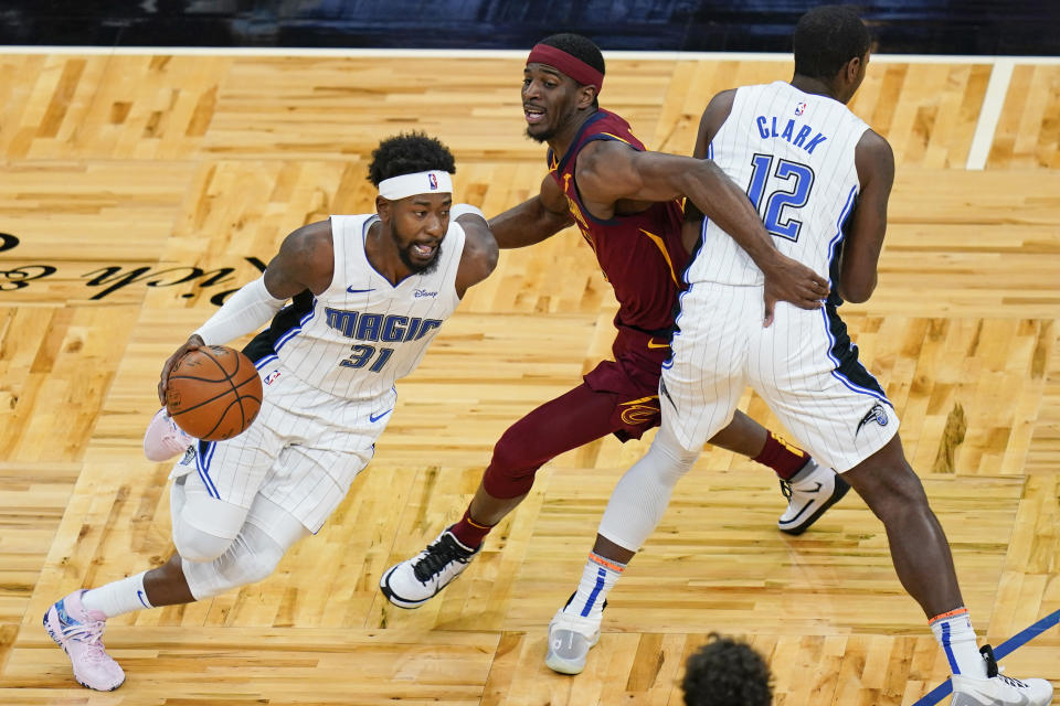 Orlando Magic guard Terrence Ross (31) drives around Cleveland Cavaliers guard Damyean Dotson, center, as forward Gary Clark (12) sets a pick during the second half of an NBA basketball game, Monday, Jan. 4, 2021, in Orlando, Fla. (AP Photo/John Raoux)