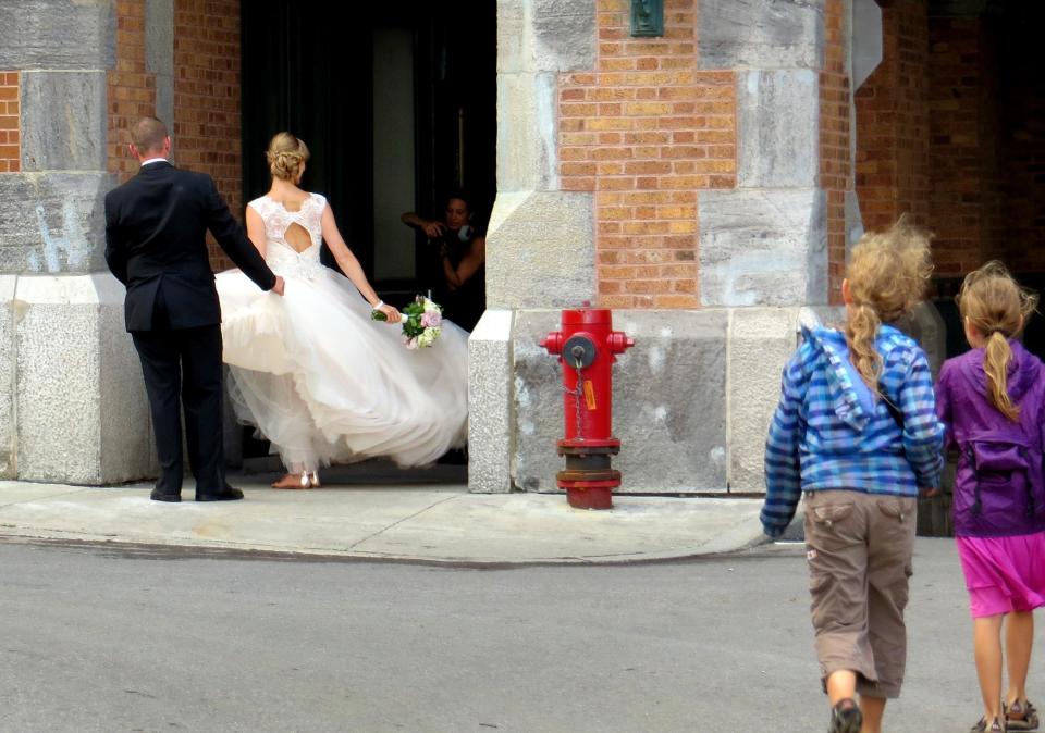 In this photo taken Aug. 13, 2013, a bride has her picture taken at Chateau Frontenac in Quebec City as curious girls watch. The chateau is an imposing icon of Quebec City's skyline. Many cyclists who bike Route Verte along the St. Lawrence River start their journey in Old Quebec. (AP Photo/R. M. Green)