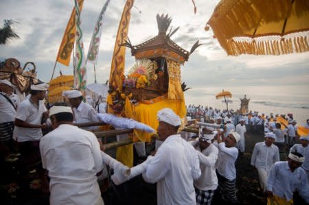 Balinese Hindu carry sacred statues of gods and deities during a Melasti purification ceremony ahead of the holy day of Nyepi, on Purnama Beach, Gianyar, Bali, Indonesia March 14, 2018 in this photo taken by Antara Foto.  Antara Foto/Nyoman Budhiana/ via REUTERS