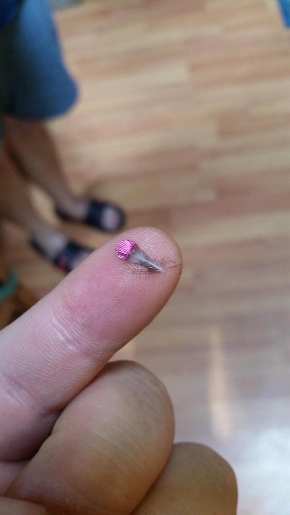 A tiny feather resting at the tip of someone's pointy finger