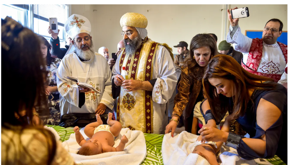 Father Girgis Ramandious, left, and His Grace Bishop Karas, center, pray over two newly baptized girls in the first Coptic Orthodox service in the former Trinity United Methodist Church building in 2018.