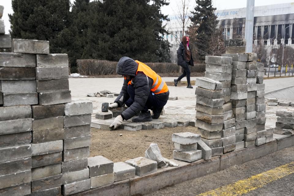 A municipal worker repairs the sidewalk at the city hall building in the central square in Almaty, Kazakhstan, Tuesday, Jan. 11, 2022. The president of Kazakhstan announced Tuesday that a Russia-led security alliance will start pulling out its troops from the country in two days after completing its mission. Life in Almaty, which was affected with the violence the most, started returning to normal this week, with public transport resuming operation and malls reopening. (AP Photo)