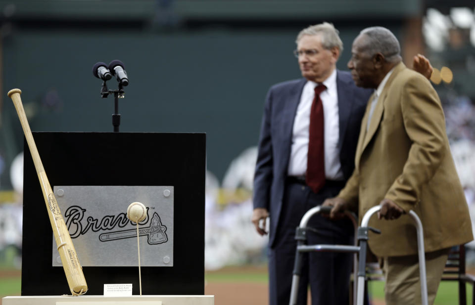 The bat and ball from Hank Aaron's 715th home run stand on display at left as Aaron, right, talks with Commissioner of Major League Baseball Bud Selig during a ceremony celebrating the 40th anniversary of the home run before the start of a baseball game between the Atlanta Braves and the New York Mets, Tuesday, April 8, 2014, in Atlanta. (AP Photo/David Goldman)