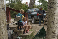 Harlee Holmes, 8, right, helps her bother, Creek, 3, put his shoes on as the family packs up to leave their home left damaged by severe flooding in Fromberg, Mont., Friday, June 17, 2022. (AP Photo/David Goldman)