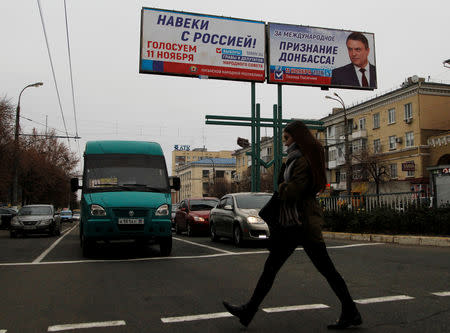 A woman crosses a street past the campaign board of Leonid Pasechnik, acting head of the self-proclaimed separatist Luhansk People's Republic (LNR), ahead of the upcoming vote for a new leader in Luhansk, Ukraine November 9, 2018. REUTERS/Alexander Ermochenko