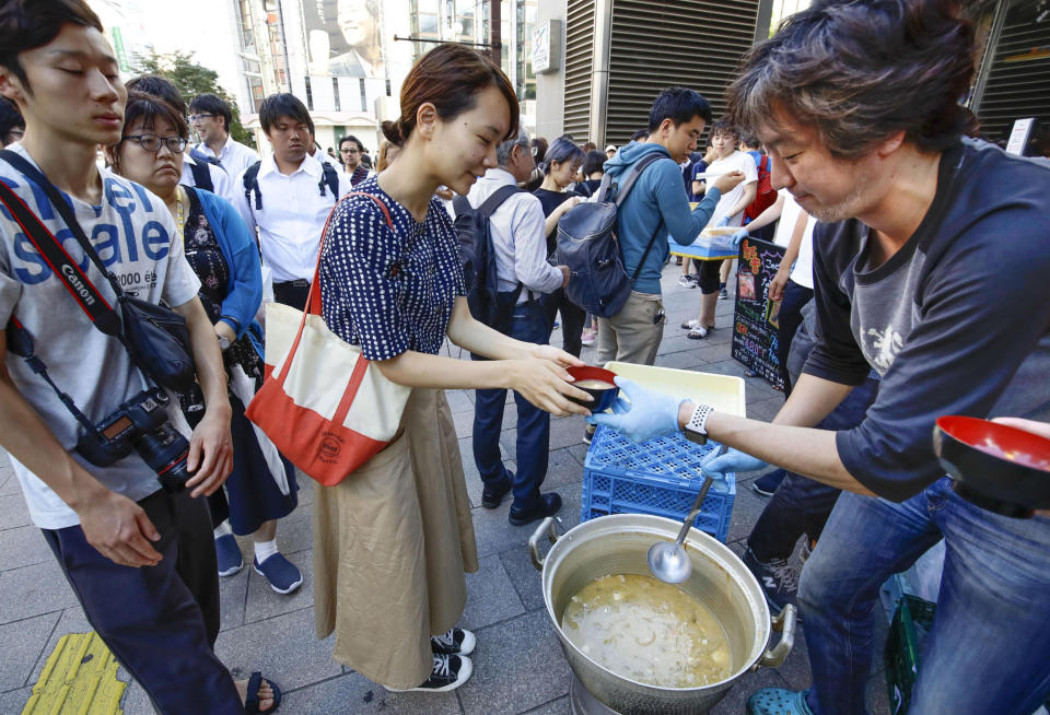 A worker of a restaurant near the area distributes soup following a powerful earthquake in Sapporo, Hokkaido, northern Japan Thursday, Sept. 6, 2018. Rescuers were rushing to unearth survivors and restore power Thursday after a powerful earthquake jolted Japan's northernmost main island of Hokkaido, buckling roads, knocking homes off their foundations and causing entire hillsides to collapse. (Hiroki Yamauchi/Kyodo News via AP)