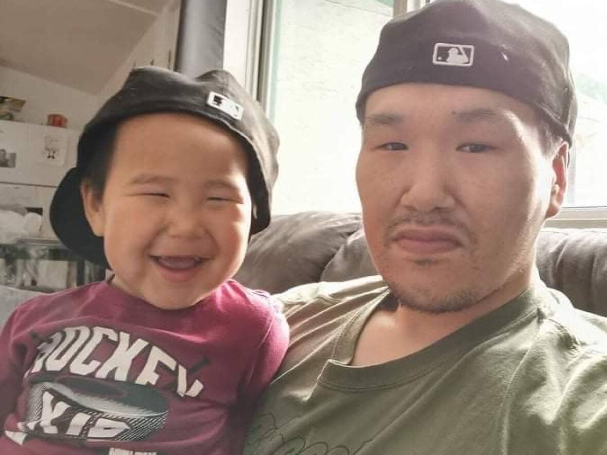 Jackson Tootoo Ell, 31, with one of his two sons, Paul. Ell moved in with his parents, who share a two-bedroom housing unit with two others, after his own unit in a fourplex was damaged by fire on Monday. (Submitted by Helen Ell-Natakok - image credit)