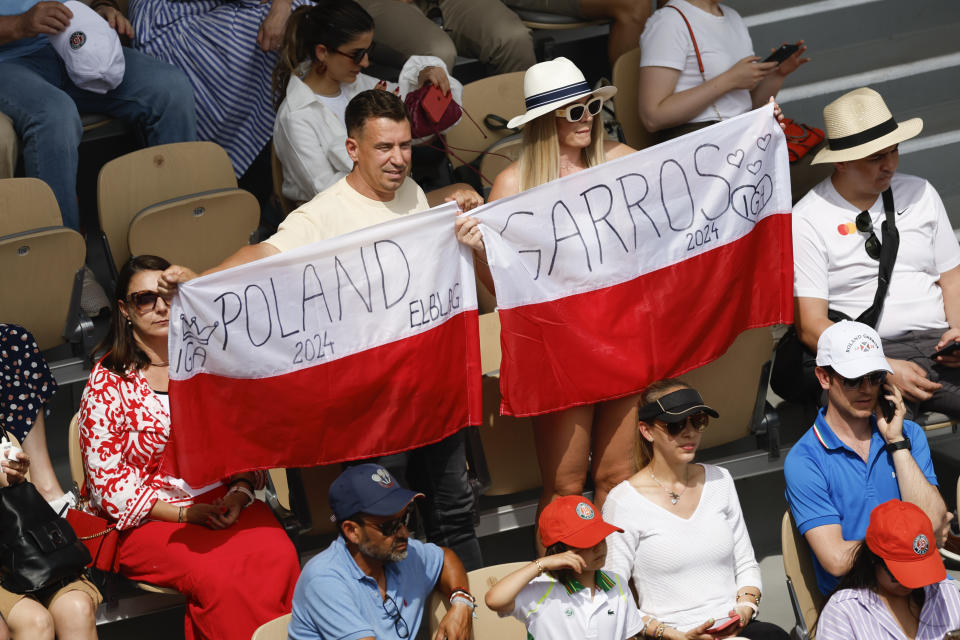 Fans of Poland's Iga Swiatek hold the national flag as she against Italy's Jasmine Paolini during the women's final of the French Open tennis tournament at the Roland Garros stadium in Paris, France, Saturday, June 8, 2024. (AP Photo/Aurelien Morissard)