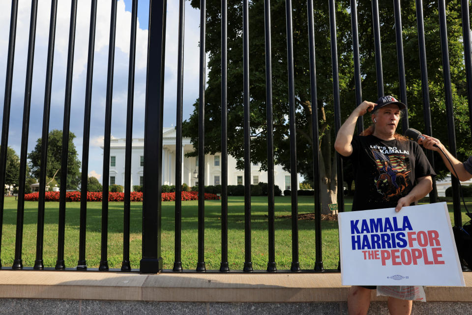 A person outside the White House holds a placard reading: Kamala Harris for the people.