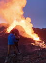 People watch as lava flows from an eruption of the Fagradalsfjall volcano on the Reykjanes Peninsula in southwestern Iceland on Thursday, May 13, 2021. (AP Photo/Miguel Morenatti)