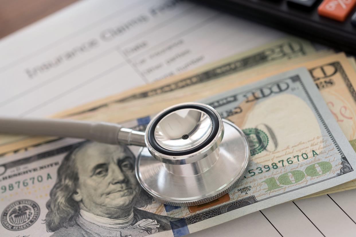 stethoscope on dollar banknote with calculator, health insurance claim form on desk