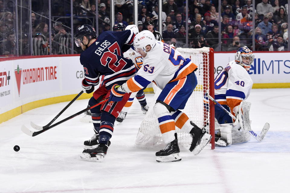 New York Islanders' Casey Cizikas (53) defends against Winnipeg Jets' Nikolaj Ehlers (27) as Islanders goaltender Semyon Varlamov (40) looks on during second-period NHL hockey game action in Winnipeg, Manitoba, Sunday, Feb. 26, 2023. (Fred Greenslade/The Canadian Press via AP)