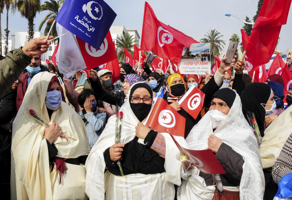 Supporters of the islamist Ennada party march with Tunisian flags during a rally in Tunis, Tunisia, Saturday, Feb. 27, 2021. The party, Ennahdha, led by House Speaker Rached Ghannouchi, has backed Prime Minister Hichem Mechichi in his standoff with President Kais Saied over a cabinet reshuffle. (AP Photo/Hassene Dridi)