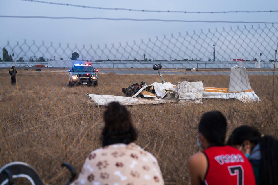 People look at the wreckage from a plane crash at Watsonville Municipal Airport in Watsonville, Calif., Thursday, Aug. 18, 2022.