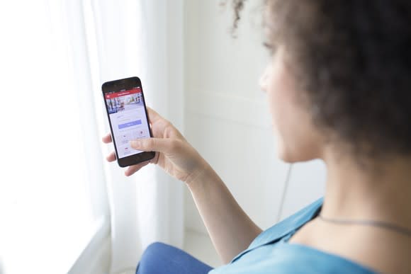 Woman using smartphone with Bank of America mobile app.