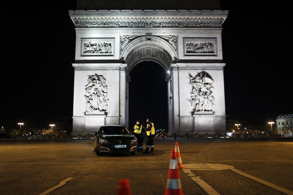 Police officers controls a car on the Champs Elysees avenue next to the Arc of Triomphe during the New Year's Eve, in Paris, Thursday, Dec. 31, 2020. As the world says goodbye to 2020, there will be countdowns and live performances, but no massed jubilant crowds in traditional gathering spots like the Champs Elysees in Paris and New York City's Times Square this New Year's Eve. (AP Photo/Thibault Camus)