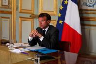 French President Emmanuel Macron listens to German Chancellor Angela Merkel during a video conference at the Elysee Palace