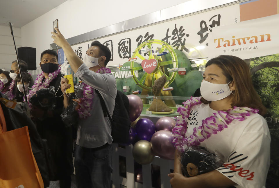 First group of foreign travelers take photos after arriving at Taoyuan International Airport in Taoyuan, Northern Taiwan, Thursday, Oct. 13, 2022. Taiwan announced that it will end mandatory COVID-19 quarantines for people arriving from overseas beginning Oct. 13. The Central Epidemic Command Center announced that the previous weeklong requirement will be replaced with a seven-day self-monitoring period. (AP Photo/Chiang Ying-ying)