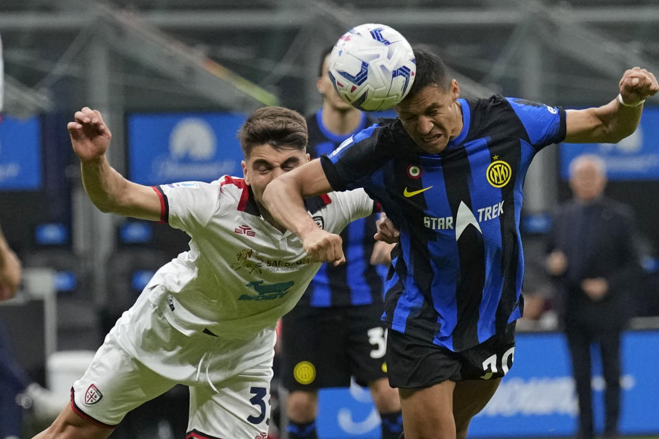 El chileno del Inter de Milán Alexis Sánchez (derecha) cabecea el balón durante el partido de la Liga de Italia ante el Cagliari en el estadio San Siro, en Milán, Italia, el domingo 14 de abril de 2024. (AP Foto/Antonio Calanni)