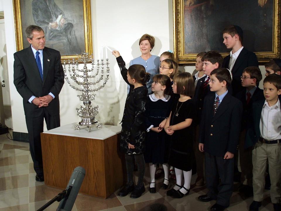 President George W. Bush and first lady Laura Bush watch 8-year-old Talia Lefkowitz light the menorah in celebration of the second day of the Hanukkah in 2001.